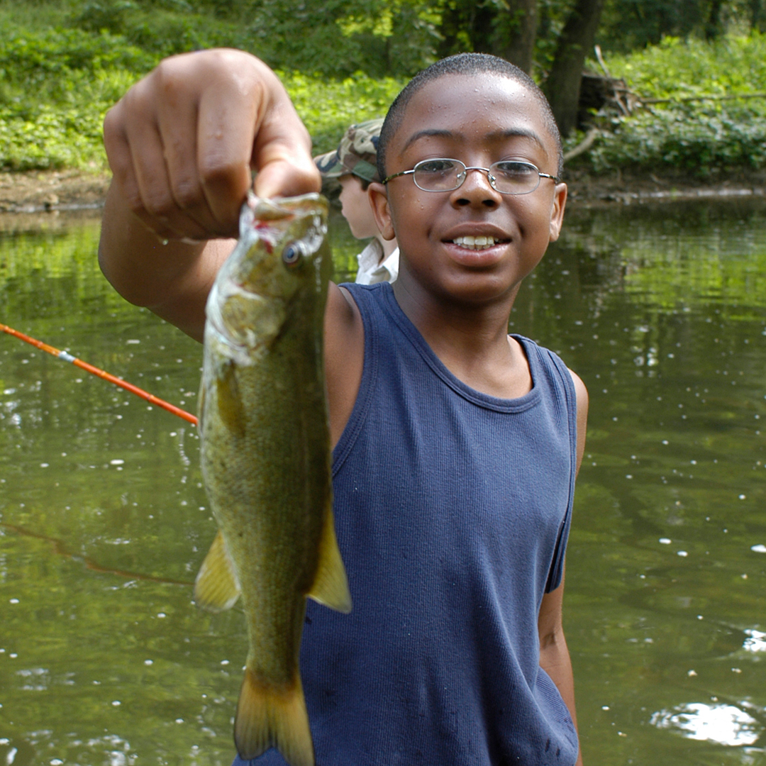 Kid smiling holding up a large fish